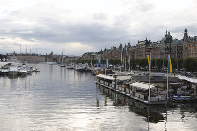 Sailboats moored in harbor against buildings in city