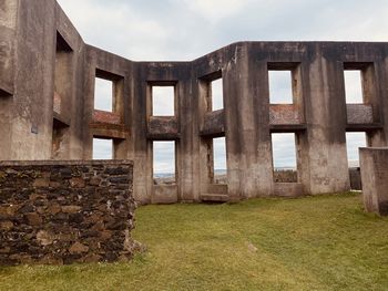 Old wooden structure on field against sky