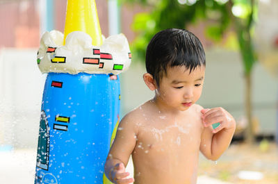 Shirtless boy looking away while enjoying in wading pool