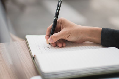 Midsection of man writing in book