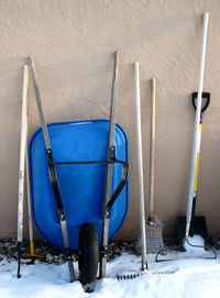 Gardening equipment on snowcapped walkway against wall