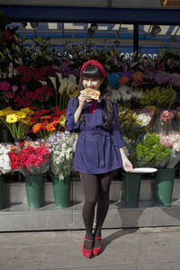 Full length of woman standing by flowering plants