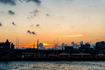 Silhouette bridge over river against sky during sunset