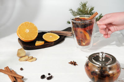 Spicy tea with cinnamon, ginger, orange and anise. hot winter tea mug. female hand holding cup of te