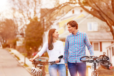Couple walking with bicycle on road