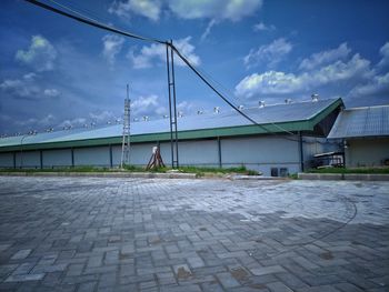 Man walking on footpath by building against sky