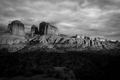 Rock formations on landscape against cloudy sky