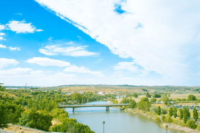 View of bridge over lake amidst trees against cloudy sky