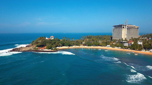 Scenic view of sea and buildings against blue sky