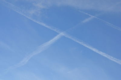 Low angle view of vapor trails in blue sky