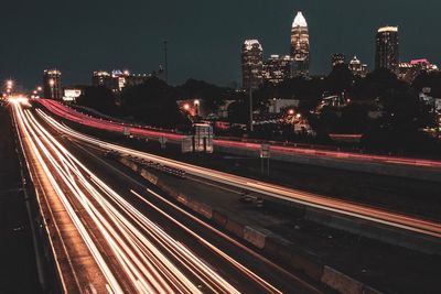 High angle view of light trails on street amidst buildings at night