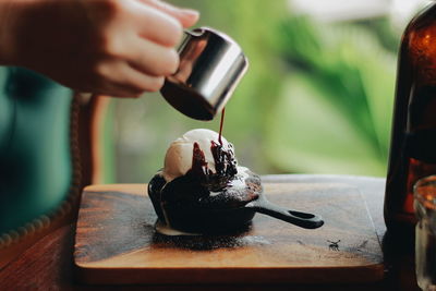 Cropped hand pouring chocolate on ice cream