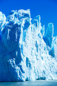 Snow covered landscape against blue sky