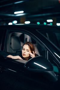 Young woman looking at side-view mirror of car