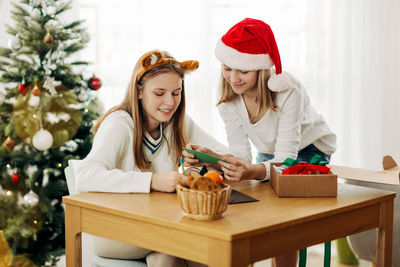 Two charming girls write greetings and wishes to friends and relatives on christmas eve 