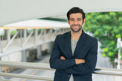 Portrait of young man standing against railing