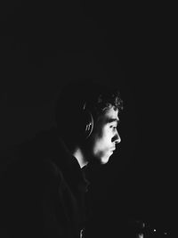 Portrait of young man looking away against black background