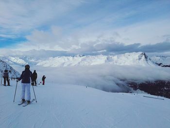 People skiing on snowcapped mountain against sky