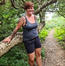 Portrait of smiling woman standing against trees