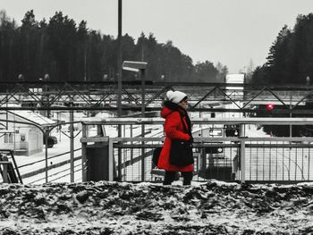 Man standing on railing during winter