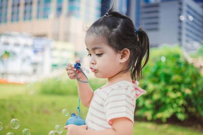 Cute girl blowing bubbles while playing at park