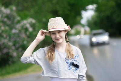 Romantic beautiful girl wearing a summer straw hat smiles on the street,car lights in the background