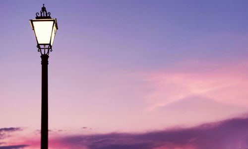 Streetlight isolated in a pink sky at sunset. lamppost lit with a cloudy and pink sky at sunset