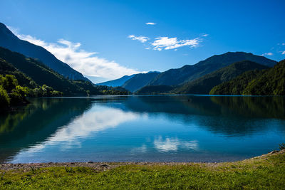 Scenic view of lake by mountains against blue sky