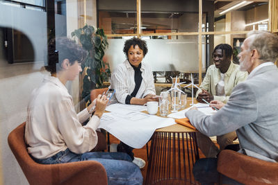 Businesswoman using smart phone with colleagues in board room at office