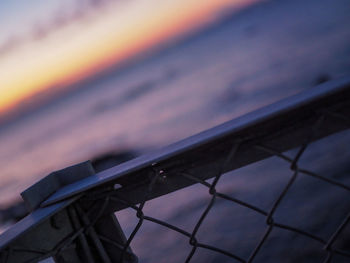 Low angle view of fence against sky at sunset