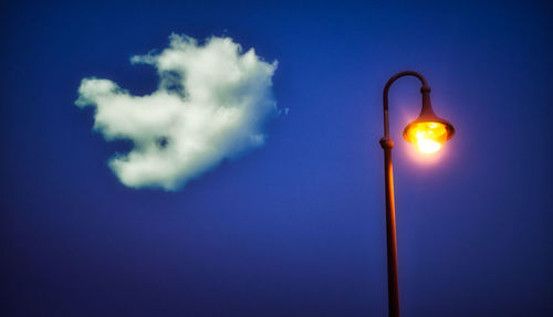 Low angle view of illuminated street light against blue sky