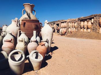 Old ceramics containers on field against clear sky