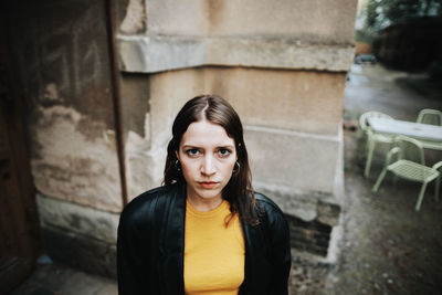 Portrait of young woman standing against wall