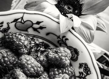 Close-up of raspberries in plate by flower