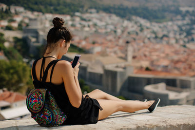 Woman using mobile phone on wall