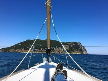 Sailboat sailing on sea against clear blue sky