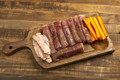 Beef roll raw to prepare with bacon and carrots on a kitchen board