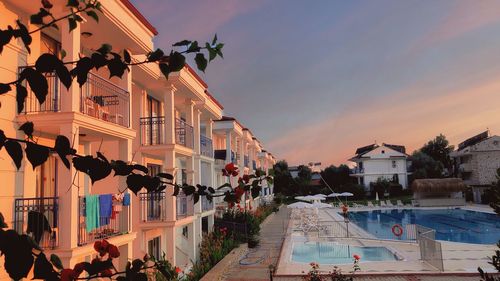 Houses by swimming pool against sky during sunset