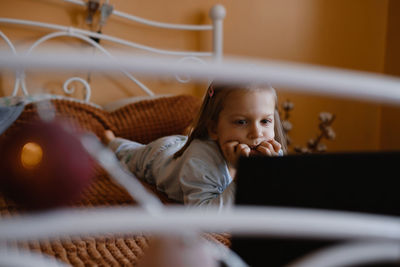 Child watching cartoons on laptop. serious kid with technology at home on bed spending time on-line