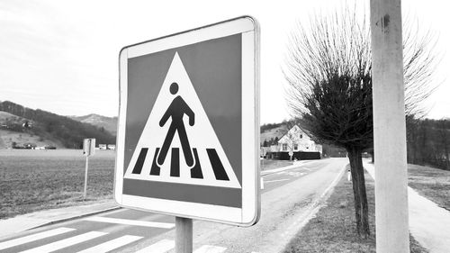 Road sign by street against sky