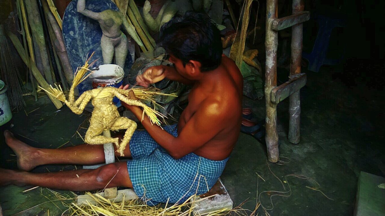 FULL LENGTH OF SHIRTLESS MAN WITH FISHING NET IN MOUTH OPEN