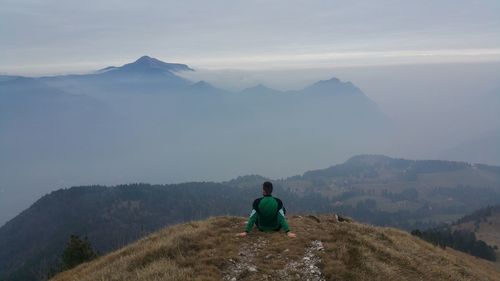 Rear view of man looking at mountains against sky