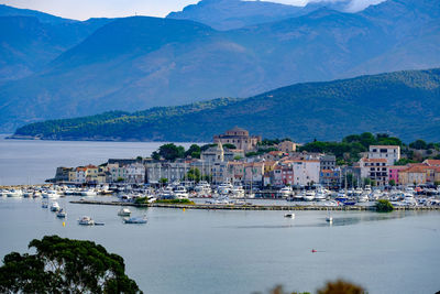 Sailboats on sea by city buildings against sky