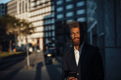 Mature businessman with mobile phone during sunny day