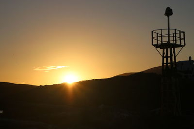 Silhouette of electricity pylon against sky during sunset