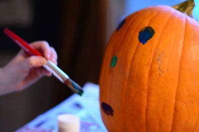 Cropped hand painting pumpkin during halloween