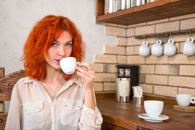 Portrait of redhead woman drinking coffee in cafe