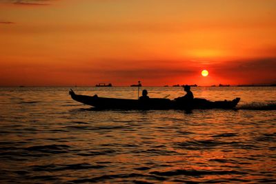 Silhouette boat in sea against orange sky