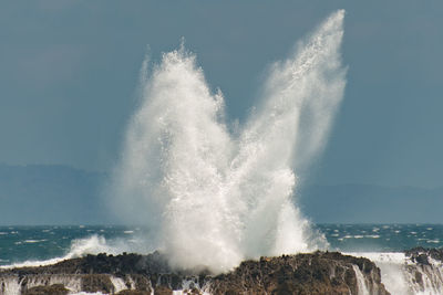 Waves splashing on sea against sky