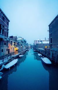 Canal amidst buildings in city against clear sky